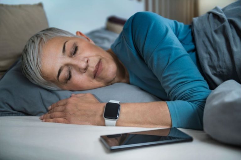 Senior Woman Sleeping in Bed, Using Smart Phone and Smart Watch